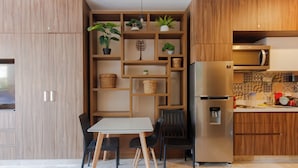 A modern kitchen with wooden cabinets, a built-in island with seating, a refrigerator, and a microwave. - Studio Caribbean Dreams (Playa del Carmen)
