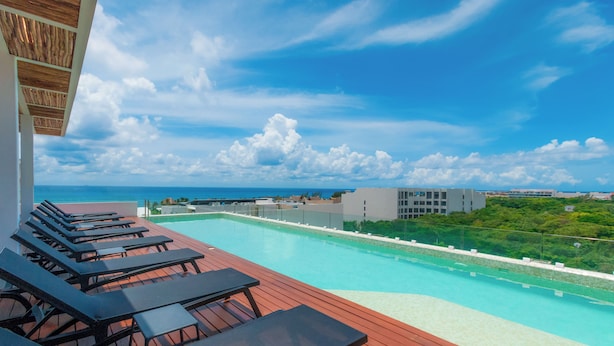A rooftop pool with lounge chairs and a clear view of the ocean. - Studio Caribbean Dreams (Playa del Carmen)
