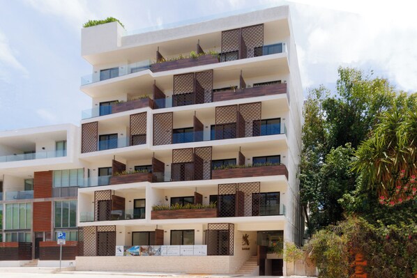 A multi-story building with balconies, large windows, and a staircase leading to the entrance.
