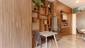 A modern kitchen with wooden cabinets, a built-in refrigerator, and a dining area with a table and chairs. - Studio Caribbean Dreams (Playa del Carmen)