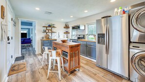 A modern kitchen with a central island, stainless steel appliances, and a view to the backyard.