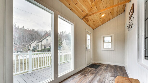 A spacious room with large windows, wooden flooring, and a high ceiling.