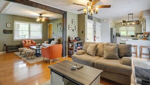 A spacious living room with a large sofa, a coffee table, and a fireplace. There is a kitchen area visible in the background. - Riverfront Shenandoah Getaway w/ Kayaks & Tubes! (Shenandoah)