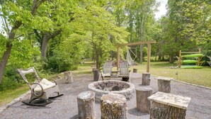 A rustic outdoor seating area with a fire pit, wooden benches, and a swing set. - Riverfront Shenandoah Getaway w/ Kayaks & Tubes! (Shenandoah)