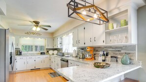 A modern kitchen with white cabinets, a granite countertop, a built-in oven, and a ceiling fan. - Riverfront Shenandoah Getaway w/ Kayaks & Tubes! (Shenandoah)