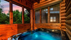 A wooden cabin with a hot tub, large windows, and a view of trees. - Mountain Retreat in the Smoky Mountain Near Dollywood (Pigeon Forge)