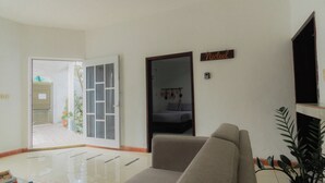 A living room with a sofa, a plant, and a door leading to a balcony. - Zayali Bacalar - Guest House (Bacalar)