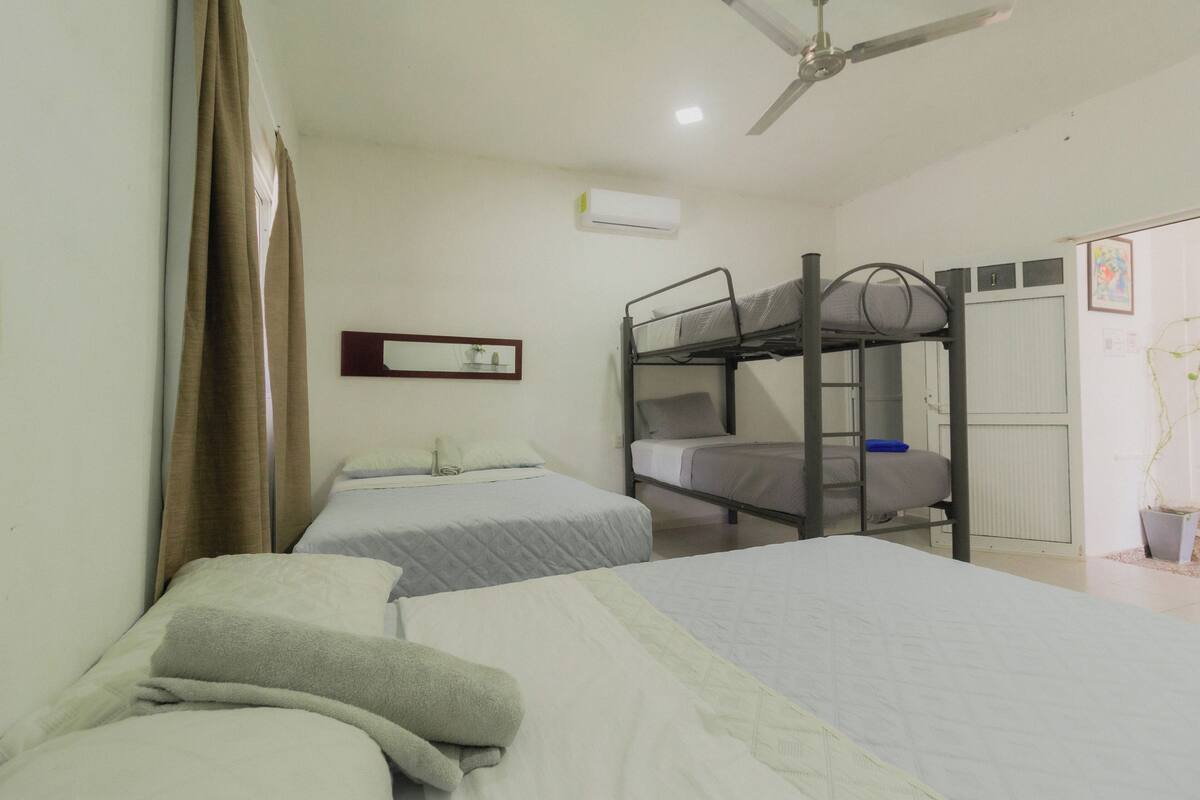 A dormitory room with bunk beds, a ceiling fan, and an air conditioning unit.