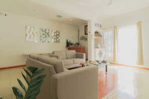 Una sala de estar con un sofá color beige, una mesa de centro con revistas y una planta.