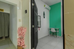 Una habitación con una pantalla verde, una silla blanca y una cesta de mimbre con flores rosas.