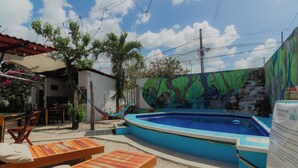 A pool area with lounge chairs, a hammock, and a mural. - Zayali Bacalar - Guest House (Bacalar)