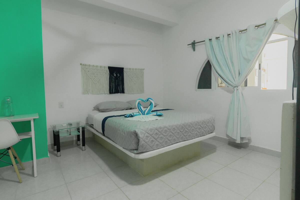 A bedroom with a bed, a desk, and a chair.