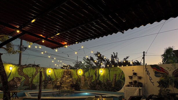 A pool area with a wooden pergola, string lights, and a mural wall. - Zayali Bacalar - Guest House (Bacalar)