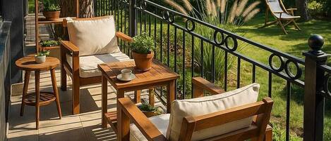 Un patio exterior con mobiliario de madera, una pequeña mesa y una planta en maceta.
