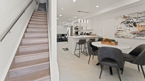 A modern kitchen with white cabinets, a central island, and bar stools. - Luxury 171-11 Condos with Magnificent Lakeviews (Leamington)