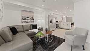 A modern living room with a grey sofa, a small round table, and a grey armchair. - Luxury 171-11 Condos with Magnificent Lakeviews (Leamington)