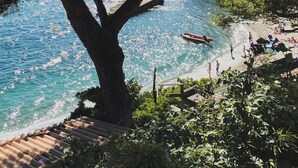 A tree-lined beach with clear water, a wooden deck, and a rocky shoreline. - Cabanon Moderne, les Pieds Dans L'eau (Le Pradet)