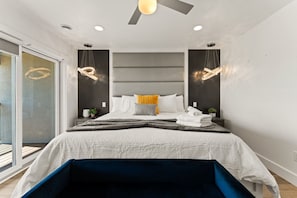Un dormitorio moderno con cama, mesitas de noche y ventilador de techo.