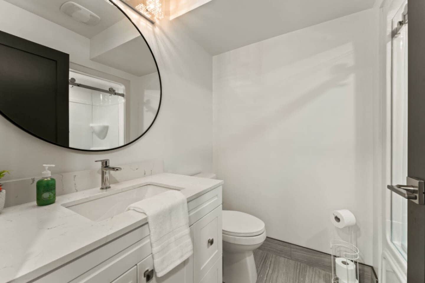 Un baño moderno con un espejo grande, lavamanos, inodoro y zona de ducha.