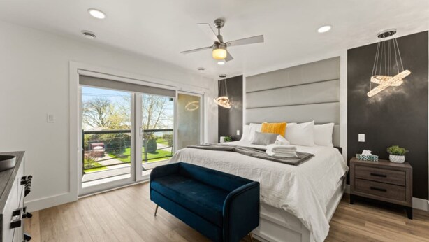 Une chambre moderne avec un grand lit, un ventilateur de plafond, un banc et une vue sur l’extérieur.