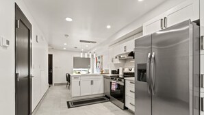 Une cuisine moderne avec des meubles blancs, des appareils en acier inoxydable et un îlot central.