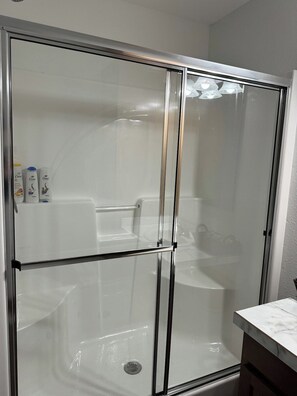 A glass-enclosed shower stall with a white bathtub and a marble countertop to the right. - Buffalo Cabin - Near T.R.N.P. (Belfield)