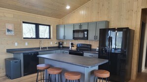 Una cocina moderna con paredes de madera, una isla central con taburetes y electrodomésticos integrados.