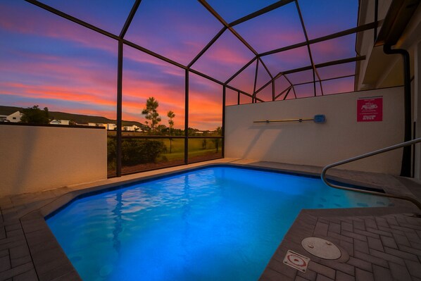 An indoor swimming pool with a view of a sunset.