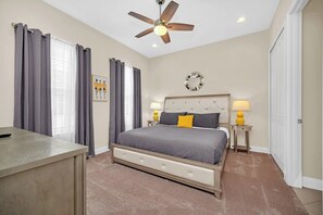A bedroom with a bed, bedside tables, a ceiling fan, and a desk.