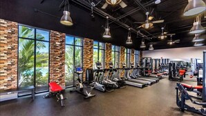Un gimnasio con cintas de correr, bicicletas estáticas y máquinas de pesas.
