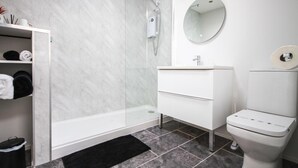 Une salle de bain moderne avec une douche à parois de verre, un meuble-lavabo blanc et des toilettes.