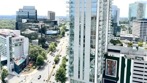 Un edificio a grattacielo con facciata in vetro moderno, circondato da altri edifici alti e una strada trafficata sottostante.