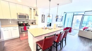 Una cucina moderna con isola centrale, elettrodomestici in acciaio inossidabile e sgabelli da bar rossi.