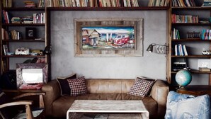 A cozy living room with a brown leather sofa, a coffee table, and a bookshelf filled with books and a globe. - Surfers Lodge Peniche (Peniche)