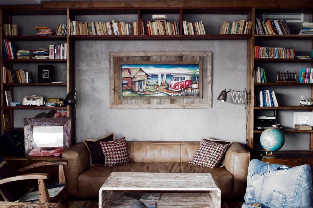 Una sala de estar acogedora con un sofá de cuero marrón, una mesa de centro y una estantería llena de libros y un globo terráqueo.
