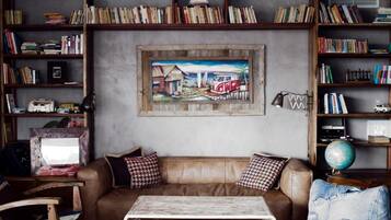 Una sala de estar acogedora con un sofá de cuero marrón, una mesa de centro y una estantería llena de libros y un globo terráqueo.