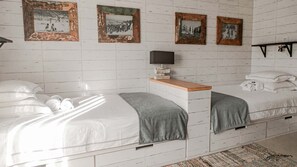 A bedroom with two beds, a TV, and framed pictures on the wall. - Surfers Lodge Peniche (Peniche)