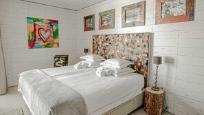 A bedroom with a bed, pillows, a bedside lamp, and a wall art piece. - Surfers Lodge Peniche (Peniche)