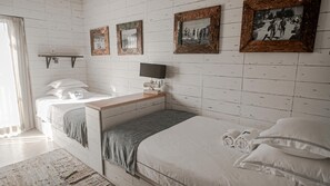 A bedroom with two beds, a bedside table, a TV, and framed pictures on the wall. - Surfers Lodge Peniche (Peniche)