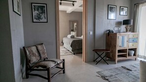 A room with a wooden chair, a small table, a cabinet, and a bed in the background. - Surfers Lodge Peniche (Peniche)