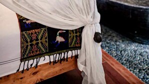 A bed with a white canopy and a colorful embroidered bedspread. - Surfers Lodge Peniche (Peniche)