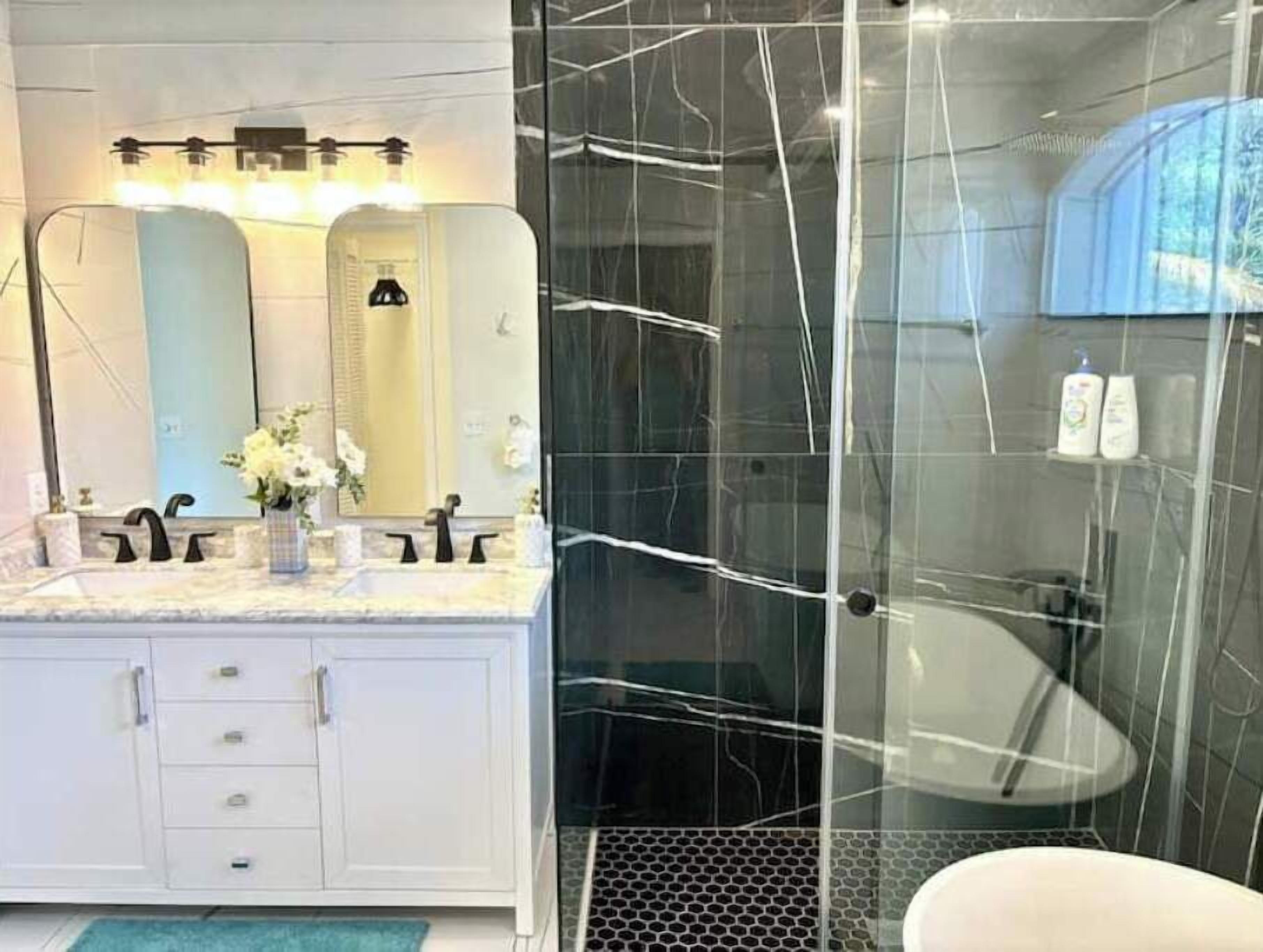 A modern bathroom with a marble vanity, a glass shower enclosure, and a large mirror.