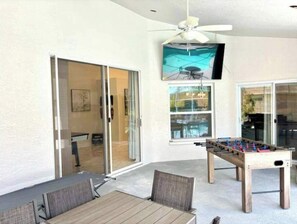 Enjoy dining and socializing in this stylish room with a large glass door offering a view of the outside, a wooden table, and a foosball table for entertainment.