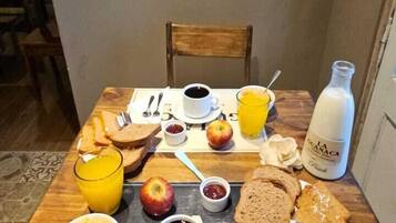 A breakfast setup with toast, fruit, coffee, and juice on a table, with a mountain painting above.