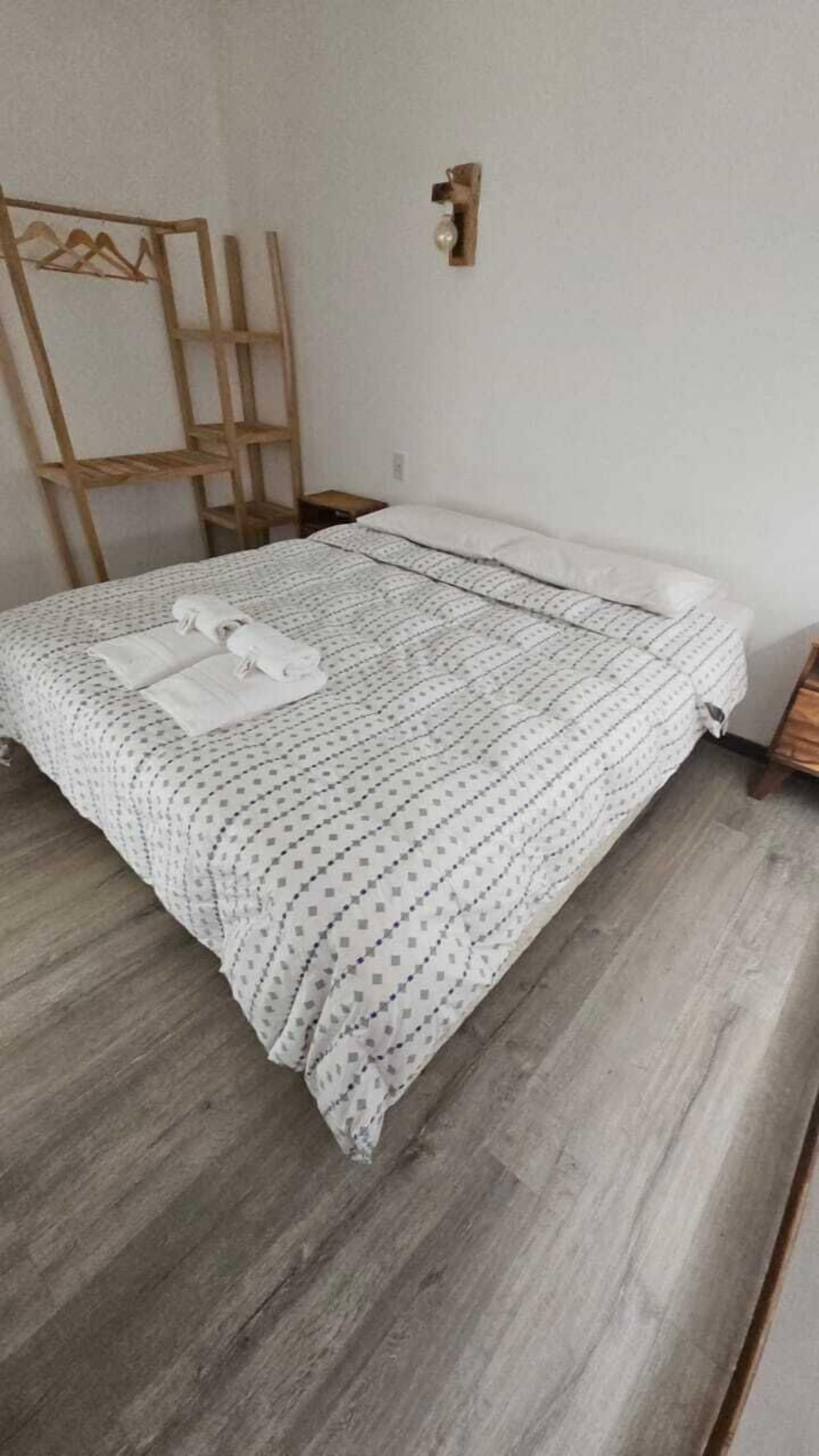 Un letto rifatto con una coperta a fantasia e due asciugamani.