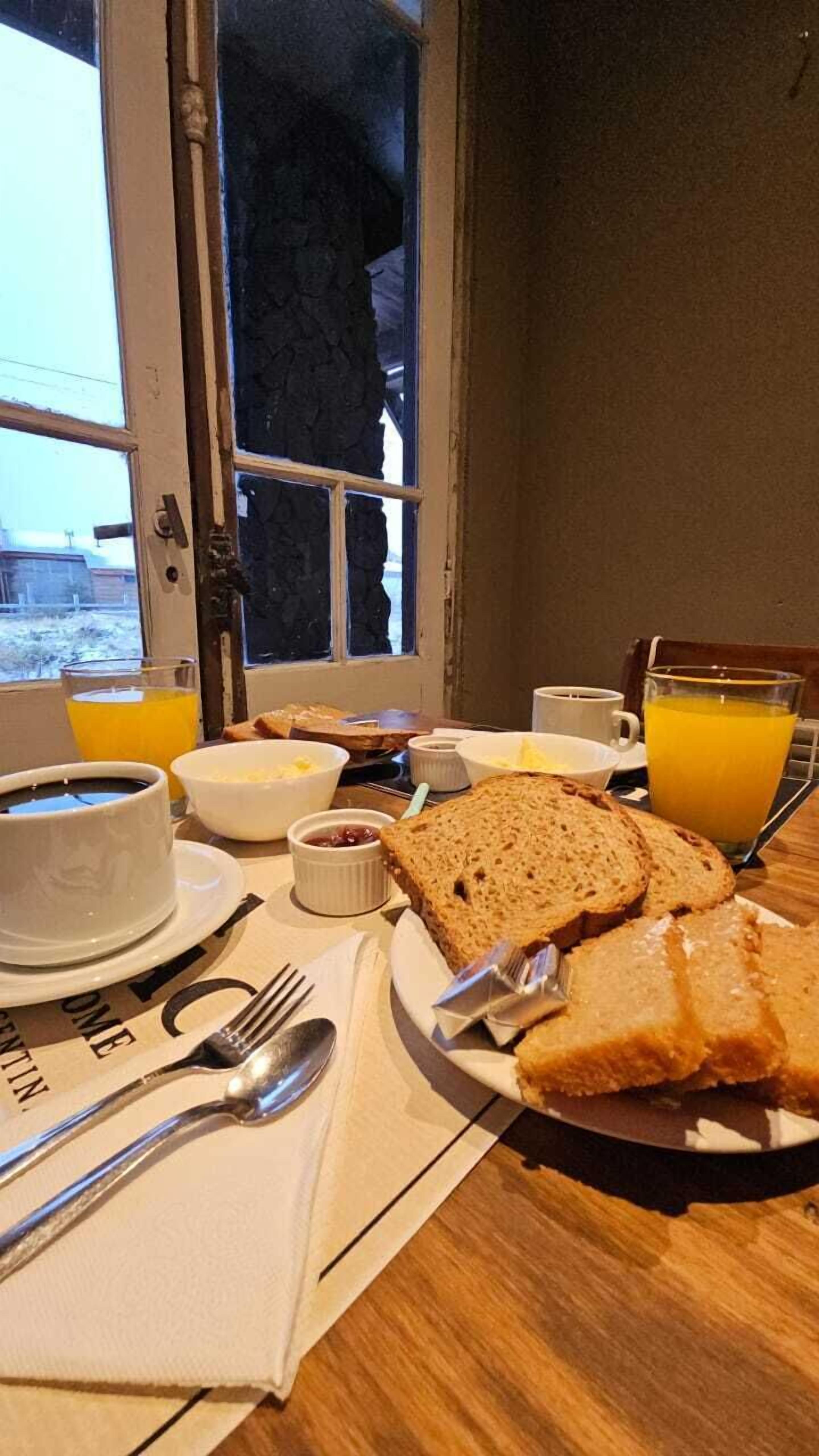 Een ontbijttafel met brood, boter, jam en sinaasappelsap.