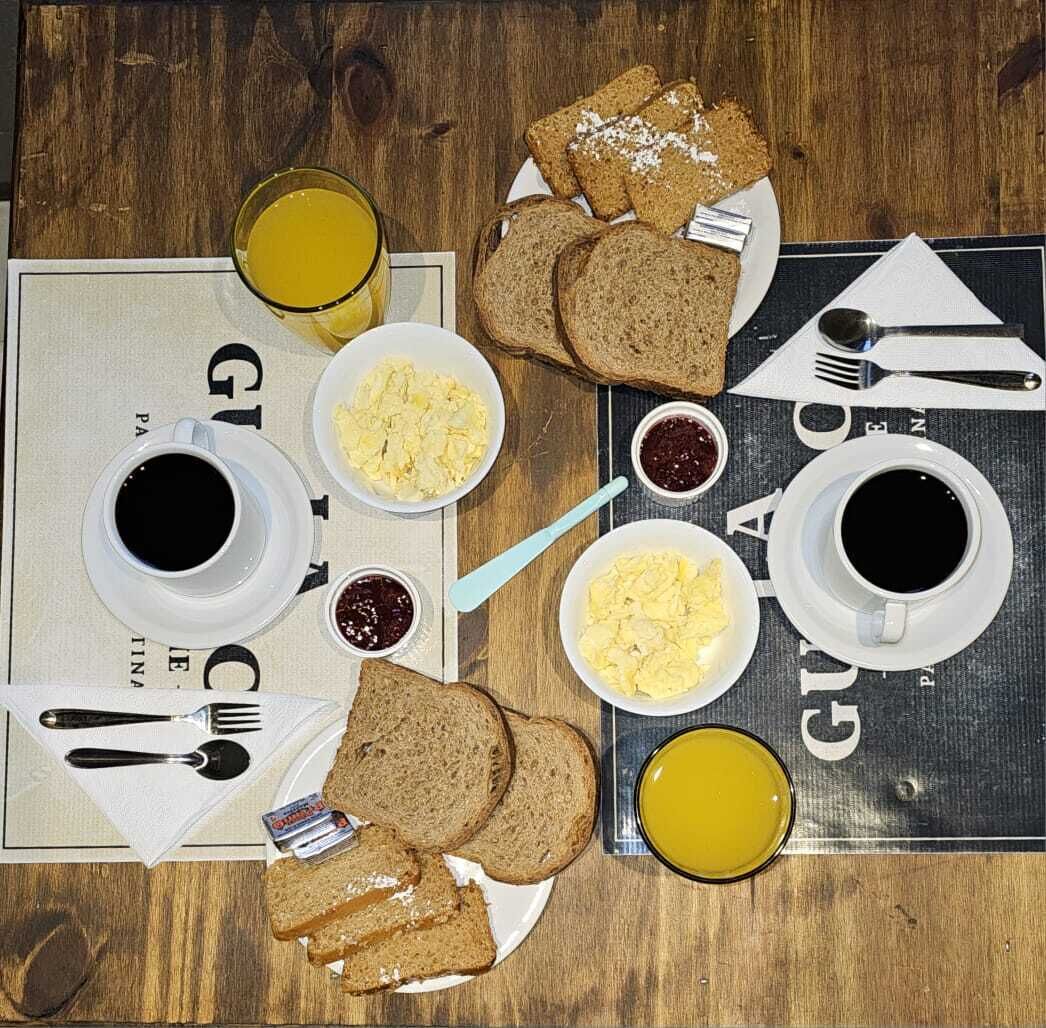 A breakfast setting with toast, scrambled eggs, and coffee on a wooden table.