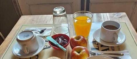 Una mesa de desayuno con tostadas, huevos revueltos, un tazón de fruta, un vaso de jugo de naranja y una taza de café.