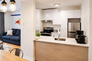 A modern kitchen with white cabinets, stainless steel appliances, and a coffee maker.