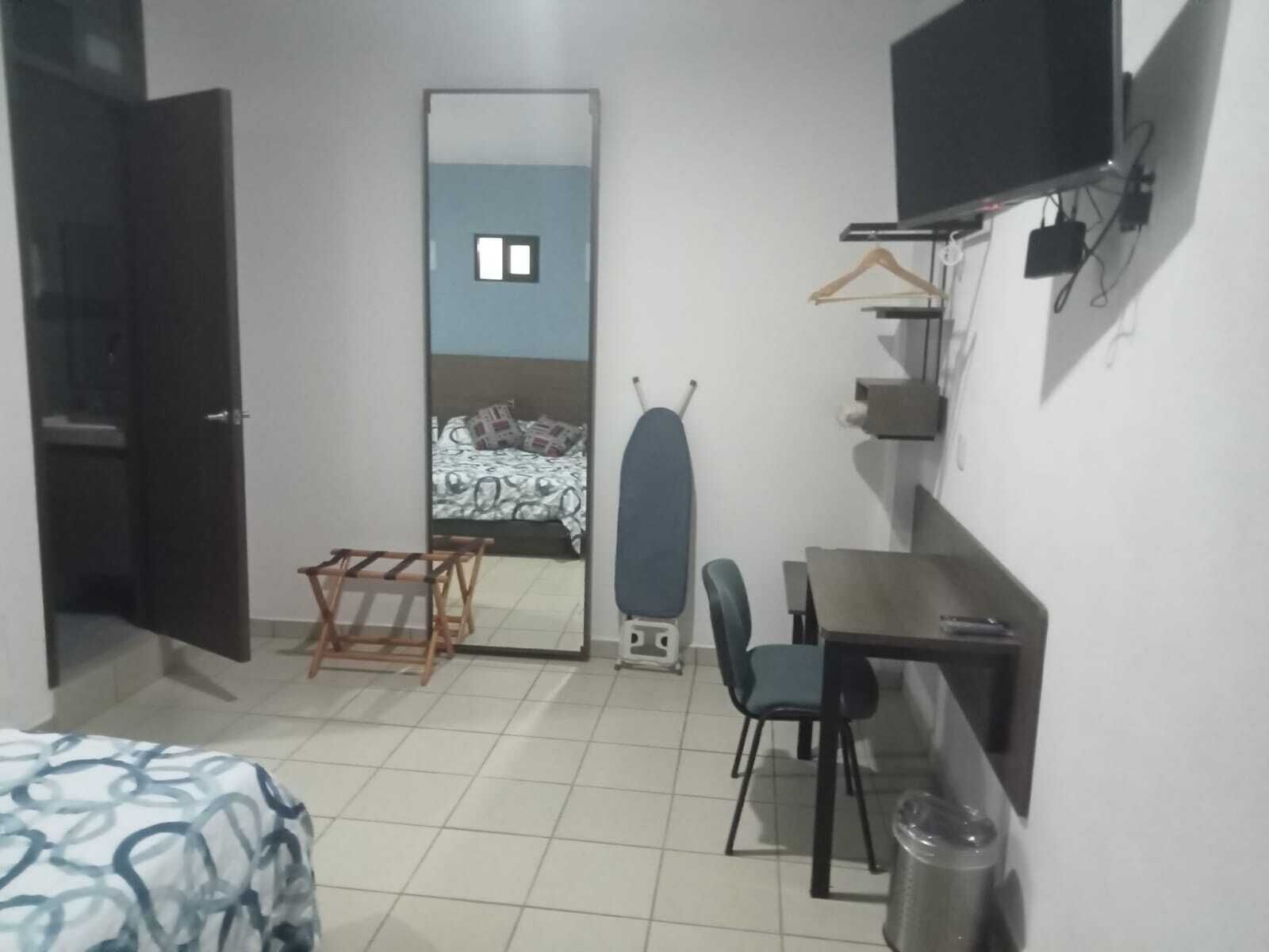 A compact hotel room with a bed, a desk, a chair, a TV, and a wardrobe.